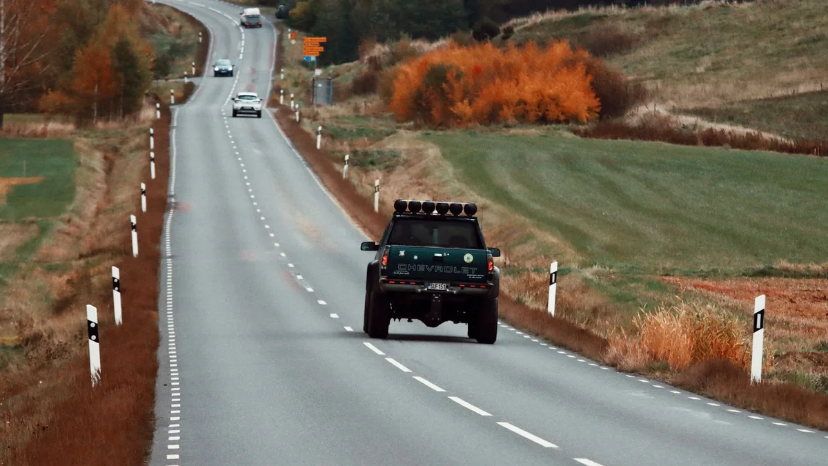 草刈りの現場へ向かう道路と、そこを走る車